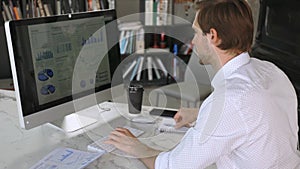 Young modern business man analyzing data using computer.