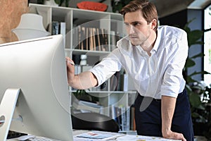 Young modern business man analyzing data using computer while working in the office.