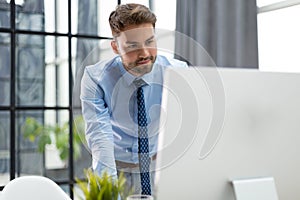 Young modern business man analyzing data using computer while working in the office.