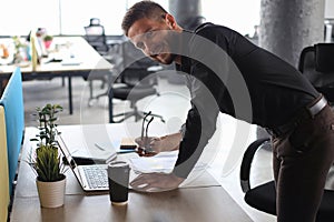 Young modern business man analyzing data using laptop while working in the office