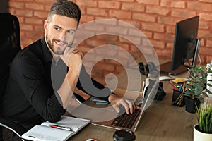 Young modern business man analyzing data using laptop while working in the office