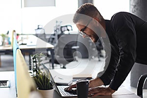 Young modern business man analyzing data using laptop while working in the office