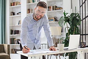 Young modern business man analyzing data using laptop while working in the office