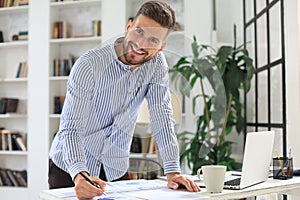 Young modern business man analyzing data using laptop while working in the office