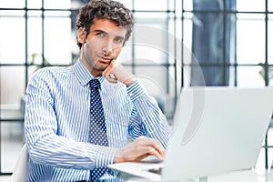 Young modern business man working using computer while sitting in the office.