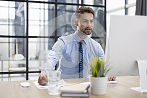 Young modern business man working using computer while sitting in the office.