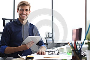 Young modern business man working using digital tablet while sitting in the office