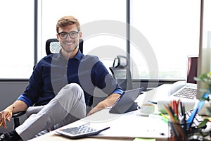 Young modern business man working using digital tablet while sitting in the office