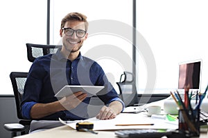 Young modern business man working using digital tablet while sitting in the office