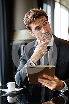 Young modern business man working using digital tablet while sitting in the office