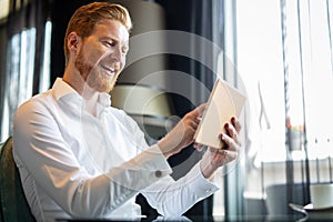 Young modern business man working using digital tablet while sitting in the office