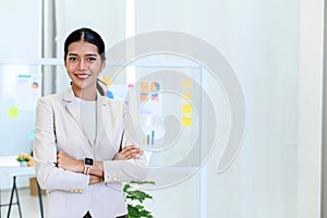young modern business woman in smart casual standing behind the glass board in the board room at the office. portrait happy busine