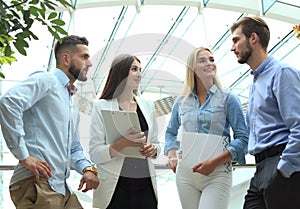 Young modern colleagues in smart casual wear having a brainstorm meeting while standing in the creative office.