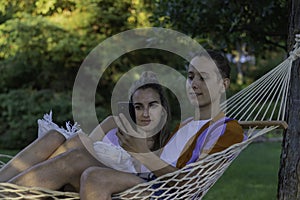 Young modern couple sitting in a hammock in holidays and vactions while looking to the smartphone sorrounded by nature photo