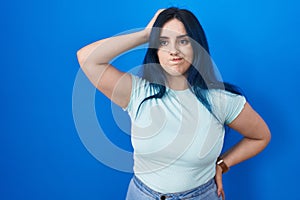 Young modern girl with blue hair standing over blue background confuse and wondering about question