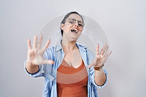 Young modern girl with blue hair standing over white background afraid and terrified with fear expression stop gesture with hands,