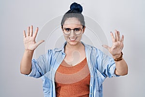 Young modern girl with blue hair standing over white background showing and pointing up with fingers number ten while smiling