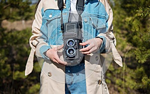 Young modern girl outdoors holding an old film retro medium format camera