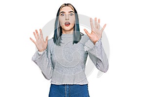 Young modern girl wearing casual sweater afraid and terrified with fear expression stop gesture with hands, shouting in shock