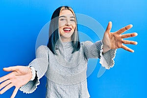 Young modern girl wearing casual sweater looking at the camera smiling with open arms for hug