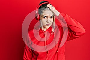 Young modern girl wearing gym clothes and using headphones confuse and wonder about question