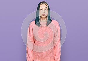 Young modern girl wearing pink wool winter sweater puffing cheeks with funny face