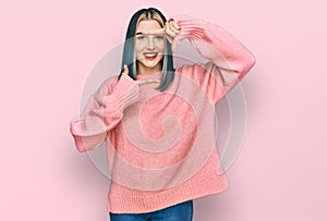 Young modern girl wearing pink wool winter sweater smiling making frame with hands and fingers with happy face