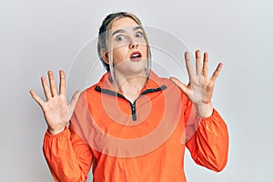 Young modern girl wearing sports sweatshirt afraid and terrified with fear expression stop gesture with hands, shouting in shock