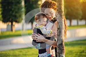 Young modern happy mom with baby son walking in Sunny Park. The concept of the joy of motherhood