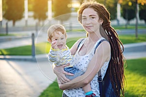 Young modern happy mom with baby son walking in Sunny Park. Concept of the joy of motherhood and autumn mood