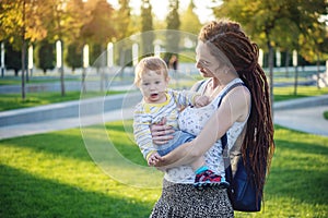 Young modern happy mom with baby son walking in Sunny Park. Concept of the joy of motherhood and autumn mood