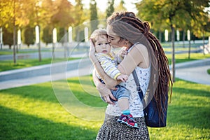 Young modern happy mom with baby son walking in Sunny Park. Concept of the joy of motherhood and autumn mood