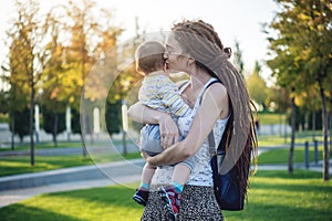 Young modern happy mom with baby son walking in Sunny Park. Concept of the joy of motherhood and autumn mood