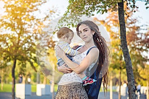 Young modern happy mom with baby son walking in Sunny Park. Concept motherhood and autumn mood