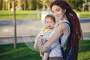 Young modern happy mom with baby son walking in Sunny Park. Joy of motherhood and autumn mood