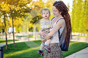 Young modern happy mom with baby son walking in Sunny Park. Joy of motherhood and autumn mood