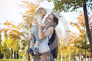 Young modern happy mom with baby son walking in Sunny Park. Motherhood and autumn mood