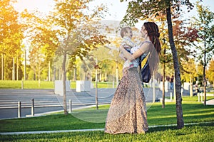 Young modern happy mom with baby son walking in Sunny Park. Motherhood and autumn mood