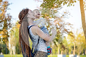 Young modern happy mom with baby son walking in Sunny Park. Motherhood and autumn mood