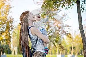 Young modern happy mom with baby son walking in Sunny Park. Motherhood and autumn mood