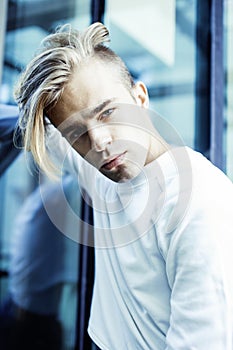 Young modern hipster guy at new building university blond fashion hairstyle having fun, lifestyle people concept