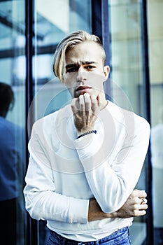 Young modern hipster guy at new building university blond fashion hairstyle having fun, lifestyle people concept