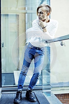 Young modern hipster guy at new building university blond fashion hairstyle having fun, lifestyle people concept