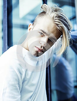 Young modern hipster guy at new building university blond fashion hairstyle having fun, lifestyle people concept