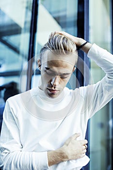 Young modern hipster guy at new building university blond fashion hairstyle having fun, lifestyle people concept