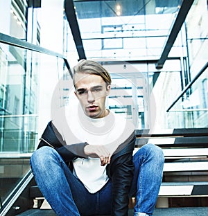 Young modern hipster guy at new building university blond fashion handsome boy, lifestyle people concept