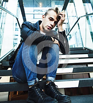 Young modern hipster guy at new building university blond fashion handsome boy, lifestyle people concept