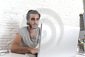 Young modern hipster style student or businessman working with laptop computer at home office