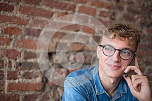 Young modern stylish businessman in glasses having cell telephone conversation