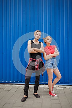Young modern stylish hipsters couple on blue background, sunny portrait couple teenagers.